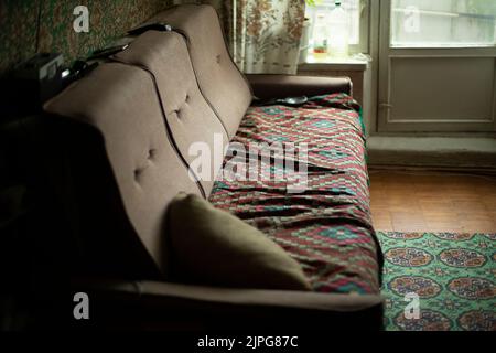 Altes Sofa im Zimmer. Möbel in der Wohnung. Interieur im alten Haus. Stockfoto