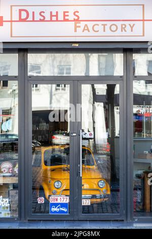 Ein kleines gelbes Auto, das in einem geschlossenen Geschirrladen geparkt wurde. Stockfoto