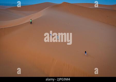 Kinder erklimmen eine Sanddüne in Merzouga, Wüste Sahara, Marokko Stockfoto