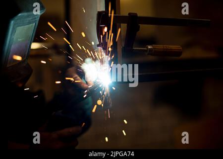 Schweißarbeiten an Metall. Blaues Feuer von hoher Temperatur. Erstellung der Schweißnaht. Funken durch Temperatur. Stockfoto