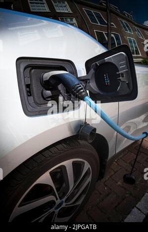 Das Elektroauto wird aufgeladen, während es auf der Straße geparkt wurde Stockfoto