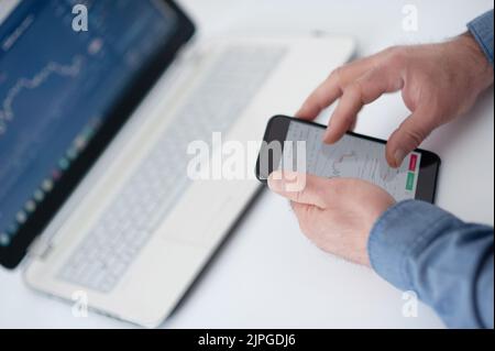 Kryptowährungen. Investmentbroker, der Bitcoin-Kryptowährung über Telefon und Laptop handelt. Trend-Trading-Konzept für Kryptowährungen. Stockfoto