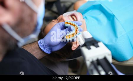 Zahnarzt hält gegossen mit Veneers auf Gipsmodell und Patient in der Zahnklinik Stockfoto