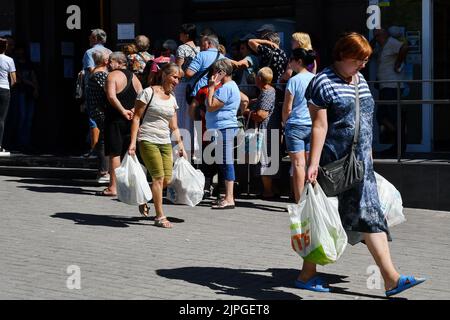 Saporischschschja, Ukraine. 8. August 2022. An einem Verteilungspunkt für humanitäre Hilfe in Saporischschschja erhalten die Menschen Nahrungsmittelhilfe. Seit Beginn der russischen Invasion wurde fast ein Drittel der Ukrainer aus ihren Häusern gezwungen. Dies ist laut dem UN-Flüchtlingshilfswerk eine der größten Vertreibungskrisen weltweit. Die Menschen in den unmittelbar von Konflikten betroffenen Gebieten benötigen dringend lebensrettende Unterstützung, es fehlt ihnen an Nahrungsmitteln, Energie und Versorgungseinrichtungen und sie stehen vor einem Zusammenbruch der Bereitstellung grundlegender Dienstleistungen. Sie sind auch mit dem Risiko von Umweltkatastrophen konfrontiert, da sie in der Nähe von h liegen Stockfoto