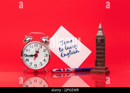 Zeit, Englisch zu lernen. Stift mit der Flagge des Vereinigten Königreichs auf rotem Hintergrund neben einer Uhr und einer Karte zum Schreiben von Nachrichten. Lernen Sie eine neue Sprache Stockfoto