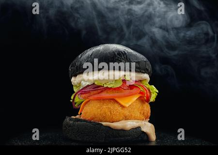 Black Burger mit Patty in Paniermehl auf schwarzem Hintergrund und Rauch Stockfoto
