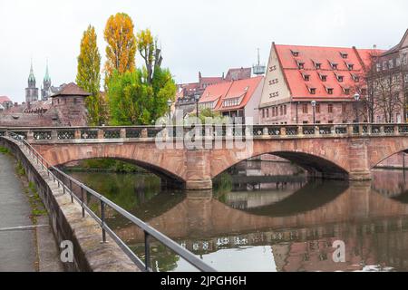 Bogenbrücke über den Fluss in Nürnberg. Altstadt im Herbst . Häuser mit Dachböden am Flussufer Stockfoto