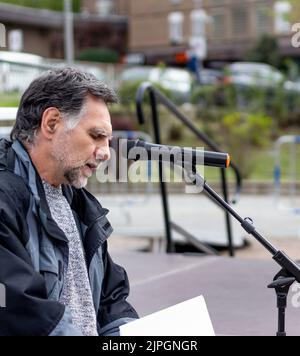Bärtiger und grauhaariger Mann spricht vor dem Mikrofon Stockfoto