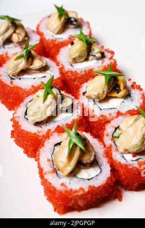 Sushi der Spitzenklasse auf weißem Hintergrund in rotem Tobiko-Kaviar mit Muscheln darauf. Essen Stockfoto