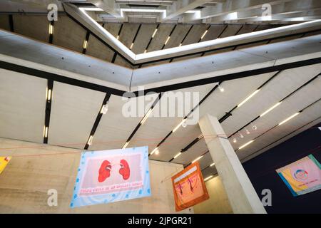 Textilien hängen im hoch aufragenden Atrium aus rohem, unfertigem Beton. In der Herzog & de Meuron entworfen Blavatnik Gebäude des Tate Modern Museum in Stockfoto