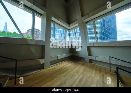 Eine schräge Fensterecke aus rohem, unvollendetem Beton mit Blick auf den Shard-Wolkenkratzer und andere Gebäude. Im Herzog & de Meuron Design Stockfoto