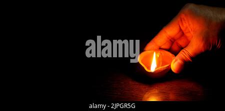 Eine Diwali-Lampe, die von Hand beleuchtet wird, Diwali-Lampen, Diwali-Diya-Lampen, die während der diwali-Feier beleuchtet werden Stockfoto