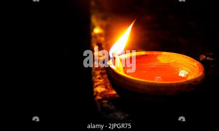 Ein Nahaufnahme-Bild einer beleuchteten Tondiya oder Lampe auf dem Boden auf Diwali - einem indischen hinduistischen Festival von Lichtern isoliert auf schwarzem Hintergrund. Stockfoto