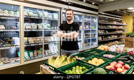 Hamburg, Deutschland. 18. August 2022. Geschäftsführer Fabian Winnersteht in dem, wie er behauptet, Hamburgs erstem Supermarkt ohne Kasse, Hoody. Die Videotechnologie weist Personen anonym Produkte zu, wenn sie etwas verpacken. Wenn sie den Store verlassen, werden sie dann automatisch über die App abgerechnet. Quelle: Markus Scholz/dpa/Alamy Live News Stockfoto