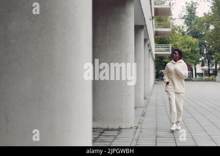 Afroamerikanische Läuferin Frau im Hoodie beim Joggen im Freien. Stockfoto