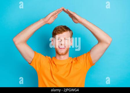 Foto von beeindruckt Ingwer Haar Kerl Arme Dach tragen orange T-Shirt isoliert auf hellblauen Hintergrund Stockfoto