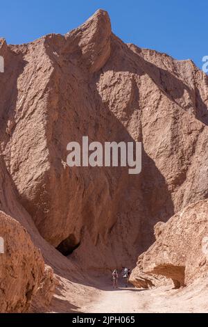 Ein paar Touristen wandern im Devil's Throat Canyon und tragen ihre beiden Kinder in Rucksäcken. Atacama-Wüste, Chile. Stockfoto