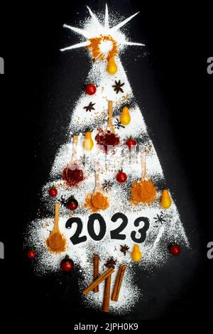 Mehrere Gewürze und Puderzucker in Form eines weihnachtsbaums und 2023 Nummern isoliert auf schwarzem Hintergrund Stockfoto