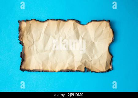 Vintage zerknittertes Papier verbrannt, Nahaufnahme isoliert auf blauem Hintergrund Stockfoto