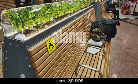 Frau müde weibliche Touristen schlafen auf Bank im Warteraum im Flughafen oder Bahnhof. Stockfoto
