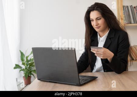 Geschäftsfrau macht Online-Shopping durch Laptop und Kreditkarte im Büro sitzen. Online-Shopping Stockfoto