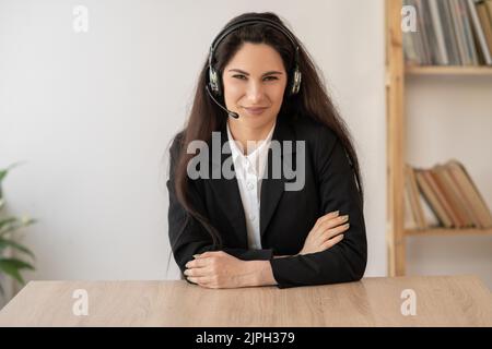 Glücklicher Callcenter-Mitarbeiter im schnurlosen Headset im Gespräch mit dem Kunden, Frau im Kopfhörer mit Mikrofon beim Kunden-Support Stockfoto
