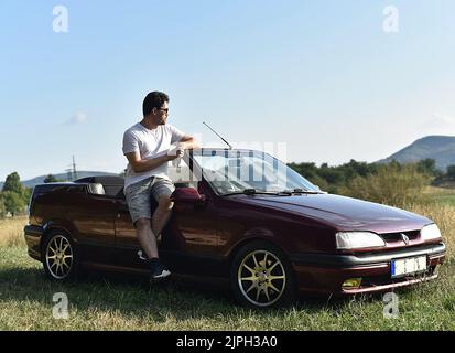 Mann lehnt sich an ein Cabrio-Oldtimer Stockfoto