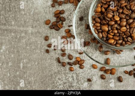 Kaffeetasse mit gerösteten Bohnen auf steingrauem Hintergrund. Draufsicht, flach liegend mit Platz für Text Stockfoto