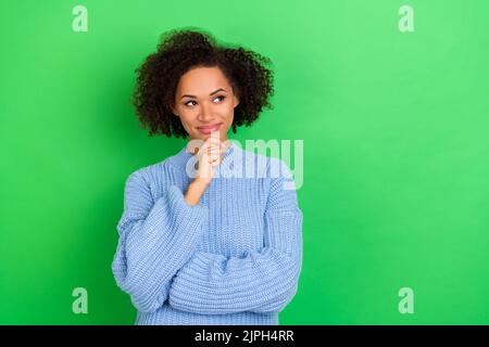 Foto von clever denkende Geschäftsfrau mit welligen Coiffure gekleidet blauen Pullover suchen leeren Raum isoliert auf grünem Hintergrund Stockfoto