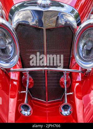 Kühlergrill aus rotem Oldtimer mit Hupen und großen Scheinwerfern an der Seite Stockfoto