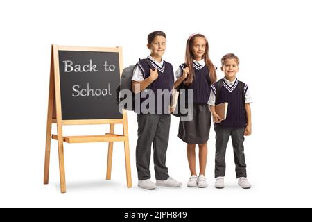 Schulkinder mit Rucksäcken stehen neben einer Tafel auf einem Stand mit Text zurück zur Schule isoliert auf weißem Hintergrund Stockfoto