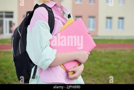 Nahaufnahme weibliche Hände mit Ordnern. Mädchen Schulmädchen in einem stilvollen farbigen gestreiften Hemd in Schulhof und Schulstadion Stockfoto