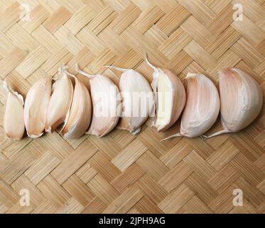 Ungeschälter Knoblauch auf einem gewebten Bambus-Hintergrund Stockfoto