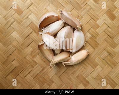 Ungeschälter Knoblauch auf einem gewebten Bambus-Hintergrund Stockfoto