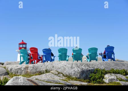 Personen, die auf Sitzplätzen sitzen, die Touristen zur Verfügung stehen, um Peggy's Cove, Nova Scotia, zu sehen Stockfoto