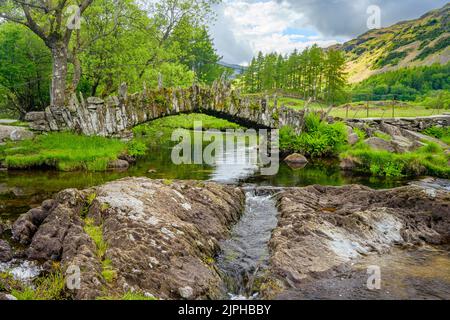 Die Slaters Bridge ist eine Packhorse-Brücke aus dem 17.. Jahrhundert, die den Fluss Brathay überquert. Stockfoto