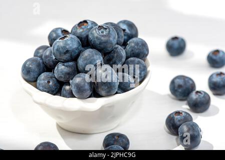 Frisch gepflückte Heidelbeeren in einer weißen Vintage-Keramikschale. Selektiver Fokus, Freier Textraum. Stockfoto