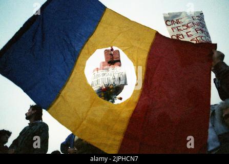 Bukarest, Rumänien, April 1990. „Golaniada“, ein großer Anti-Kommunismus-Protest auf dem Universitätsplatz nach der rumänischen Revolution von 1989. Die Menschen versammelten sich täglich, um gegen die Ex-Kommunisten zu protestieren, die nach der Revolution die Macht ergriffen hatten. Die rumänische Flagge mit dem abgeschnittenen sozialistischen Emblem war während der Revolution ein antikommunistisches Symbol. Stockfoto