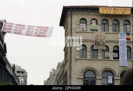 Bukarest, Rumänien, April 1990. „Golaniada“, ein großer Anti-Kommunismus-Protest auf dem Universitätsplatz nach der rumänischen Revolution von 1989. Die Menschen versammelten sich täglich, um gegen die Ex-Kommunisten zu protestieren, die nach der Revolution die Macht ergriffen hatten. An den Wänden des Universitätsgebäudes hängen verschiedene Banner. Einer von ihnen zeigt Diktator Ceausescu und Präsident Iliescu mit der Erklärung "Freunde". Stockfoto