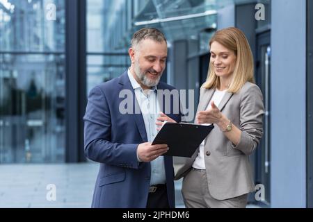 Zwei Geschäftskollegen Mann und Frau sprechen und diskutieren Arbeitsprozess, eine Gruppe von Kollegen außerhalb des Bürogebäudes Stockfoto
