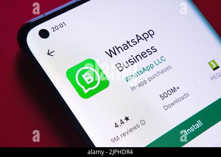 whatsapp Business App im Google Play Store auf dem Smartphone-Bildschirm auf rotem Hintergrund gesehen. Nahaufnahme mit selektivem Fokus. Stafford, Einheit Stockfoto