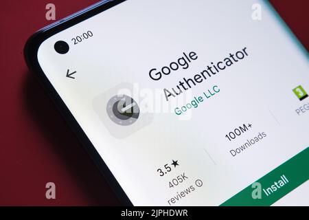 Google Authenticator App im Google Play Store auf dem Smartphone-Bildschirm auf rotem Hintergrund platziert gesehen. Nahaufnahme mit selektivem Fokus. Stafford, U Stockfoto