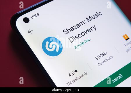 Shazam App im Google Play Store auf dem Smartphone-Bildschirm auf rotem Hintergrund platziert gesehen. Nahaufnahme mit selektivem Fokus. Stafford, Vereinigtes Königreich, Stockfoto