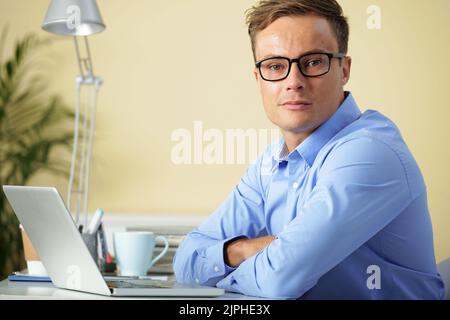Porträt eines jungen, hübschen Programmentwicklers in einer Brille, der die Kamera anschaut Stockfoto