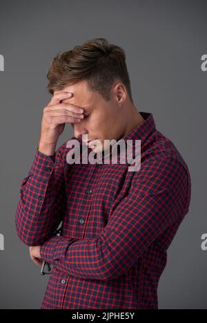 Trauriger Mann, der unter Kopfschmerzen oder emotionalem Stress leidet Stockfoto
