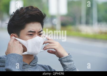 Gesicht des asiatischen jungen Mannes mit Gesichtsmaske Stockfoto