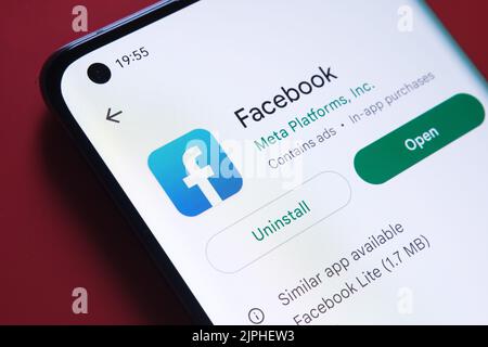 facebook-App im Google Play Store auf dem Smartphone-Bildschirm auf rotem Hintergrund zu sehen. Nahaufnahme mit selektivem Fokus. Stafford, Großbritannien Stockfoto