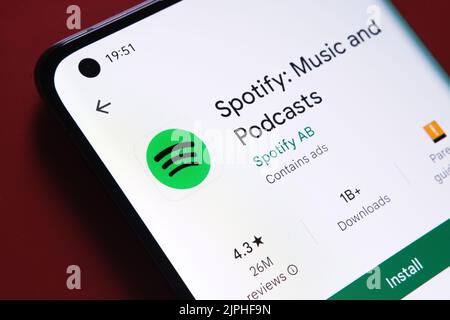 spotify-App im Google Play Store auf dem Smartphone-Bildschirm auf rotem Hintergrund angezeigt. Nahaufnahme mit selektivem Fokus. Stafford, Großbritannien Stockfoto