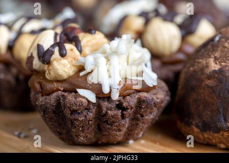 Mehrkomponentenkuchen aus Karamell und Nüssen in Schokolade, gemischter Haselnusskuchen mit Mandeln und Karamell Stockfoto