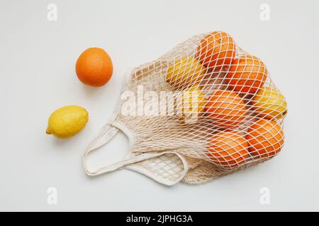 Zitrusfrüchte im wiederverwendbaren Beutel auf weißem Hintergrund, flach liegend, Draufsicht, Kopierraum Stockfoto
